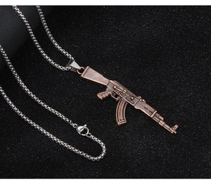 Detailed close-up of AK-47 rifle pendant in bronze finish with silver box chain