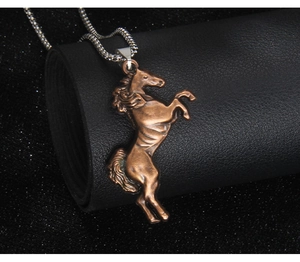 Detailed close-up of a vintage bronze galloping horse pendant on a silver box chain