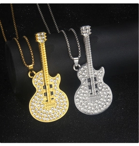Close-up of gold and silver guitar necklaces with pave-set rhinestones on a black display
