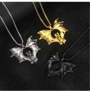 Detailed bat pendant necklaces in silver, gold, and black finishes on a textured surface