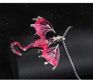 Close-up of pink dragon pendant with colorful rhinestones on black textured display