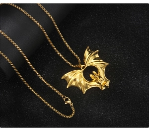 Detailed close-up of a golden gothic bat pendant with a lobster clasp on a dark background