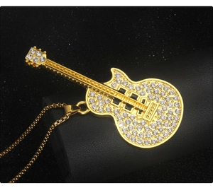 Macro shot of gold-plated guitar necklace with sparkling rhinestones on black leather roll