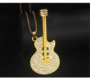 Macro shot of gold guitar pendant necklace with white crystals on black leather