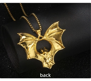 Detail of the back of a gold bat pendant with 1932 engraving on a black leather stand