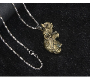 Detail of vintage bronze elephant pendant with intricate carvings and silver square chain