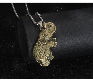 Detailed macro view of vintage bronze elephant pendant with engraved floral patterns