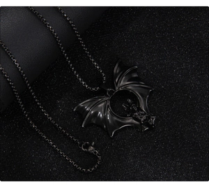 Detailed view of black gothic bat pendant with circular relief on dark leather background