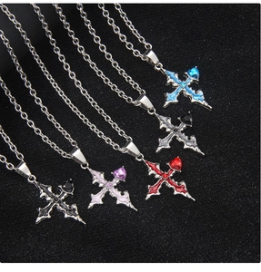 Close-up of five gothic cross necklaces with colorful heart stones on black textured surface