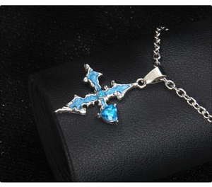 Detail of gothic stainless steel cross necklace with blue enamel and heart gemstone