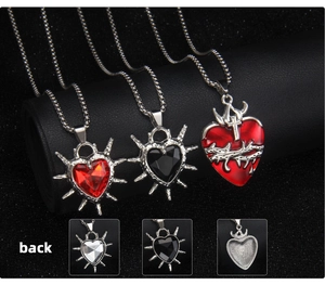 Dettaglio di pendenti a cuore gotico con spine su texture in pelle scura