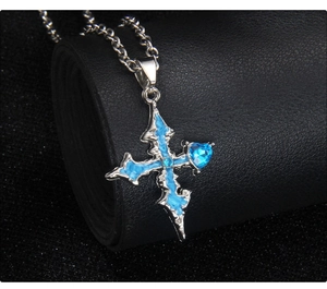 Macro detail of gothic silver cross pendant with blue heart gemstone and enamel