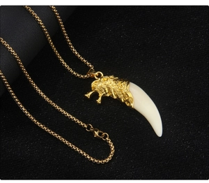 Macro shot of gold wolf head pendant with resin tusk and sleek box chain necklace