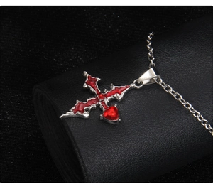 Detailed close-up of gothic cross pendant with red heart crystals on black leather background