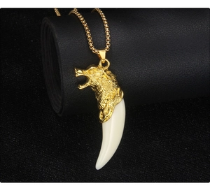 Detail of golden wolf head pendant with white resin tooth on a black leather scroll