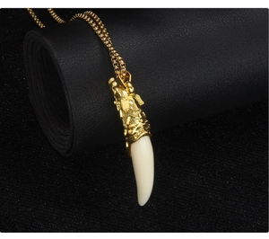 Detail of golden dragon head pendant with white faux wolf tooth on black leather