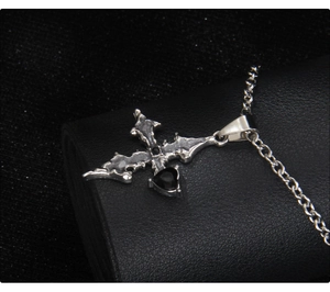 Macro shot of Gothic silver cross necklace featuring a glossy black heart pendant
