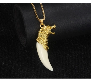 Macro shot of gold wolf head pendant with ivory resin fang on a black leather base