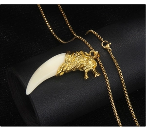 Detail of a men's gold wolf head pendant necklace with a white resin fang on black leather