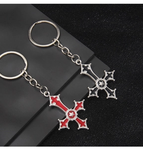 Detail of red and black Gothic cross keychains with engraved star pattern and alloy texture