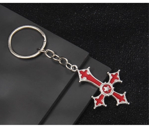 Close-up of red enamel cross keychain with a silver star on a dark textured background