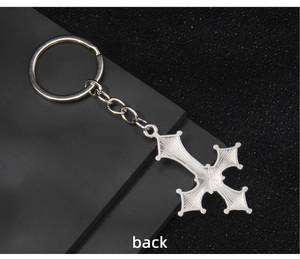 Detailed back view of a silver-tone metal cross keychain with radial textured patterns
