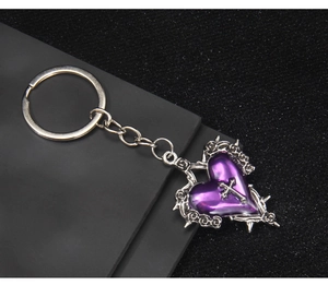 Close-up of gothic purple heart keychain with silver cross and thorn metal frame