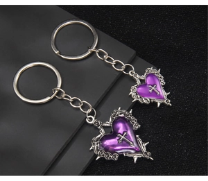 Gothic purple resin heart keychain with metal cross and rose thorns detail on dark background