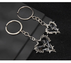 Detail of gothic heart keychains with black drip oil, silver cross and thorn rose textures