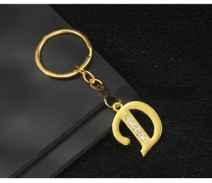 Close-up of golden letter D keychain featuring five inlaid clear sparkling zircons