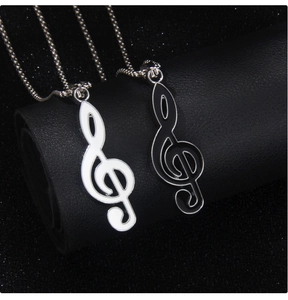 Detail of black and white enamel treble clef necklaces on a leather display stand