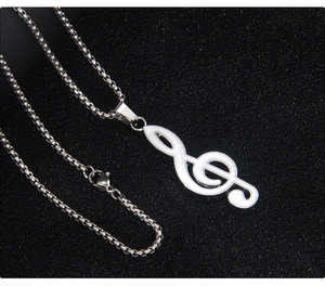 Detailed shot of the white enamel treble clef pendant with a silver box chain necklace