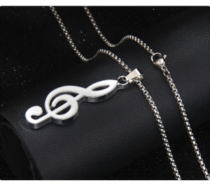 Detailed close-up of a silver G-clef musical note pendant on a polished steel chain