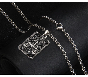 Gros plan du pendentif carte de tarot Justice en argent et noir sur du cuir