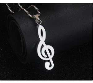 Macro detail of silver treble clef music note pendant with white enamel inlay