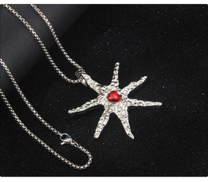 Macro detail of starburst necklace with hammered silver texture and red heart gemstone