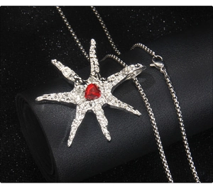 Detailed macro view of silver star pendant with textured surface and red heart gem