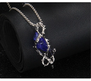 Détail du collier gothique avec cœur en résine bleu foncé et cadre d'épines argentées