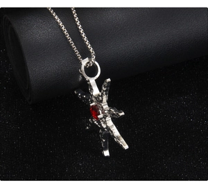 Detail of silver starfish necklace with red crystal on black textured background