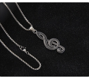 Detail of music treble clef pendant with black enamel finish and silver round box chain