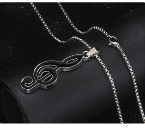 Macro view of a silver and black treble clef music note pendant with box chain detail