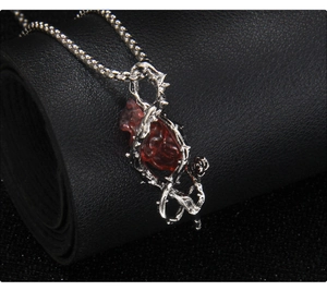 Détail du pendentif gothique en épines avec pierre de cœur rouge sur cuir noir