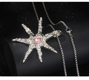 Detailed macro of silver star pendant with textured metal and pink heart gemstone