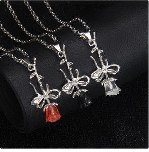 Gros plan de trois colliers à pendentif rose en rouge noir et transparent sur support