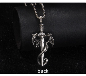 Vue macro du dos d'un pendentif épée de dragon argenté vintage sur une surface noire