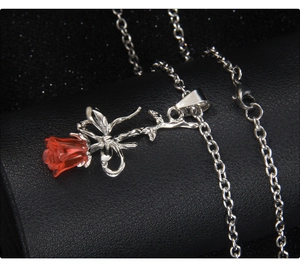 Gros plan du pendentif rose rouge 3D avec tige argentée et nœud sur une chaîne collier