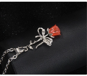 Gros plan d'un pendentif rose rouge 3D avec nœud argenté sur cuir noir texturé