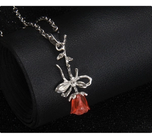 Gros plan détaillé du pendentif rose rouge 3D avec tige argentée sur fond noir élégant
