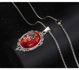 Detailed close-up of gothic oval red gemstone pendant with rose relief and silver bezel