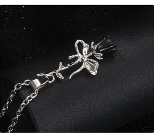 Gros plan d'un collier pendentif rose argentée 3D avec bouton noir sur cuir